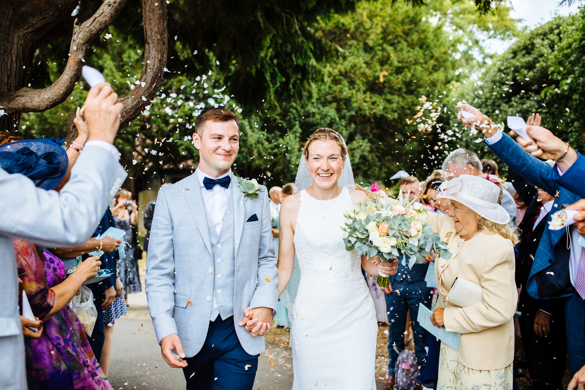 everyone throwing confetti on bride and groom as they walk down the church path at kentfield farm wedding