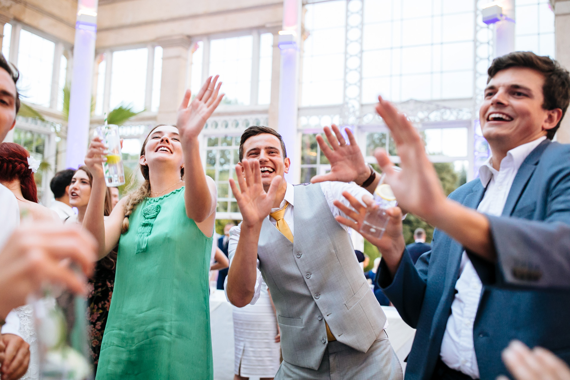 groom and friends putting hands up in the air and dancing at syon park wedding