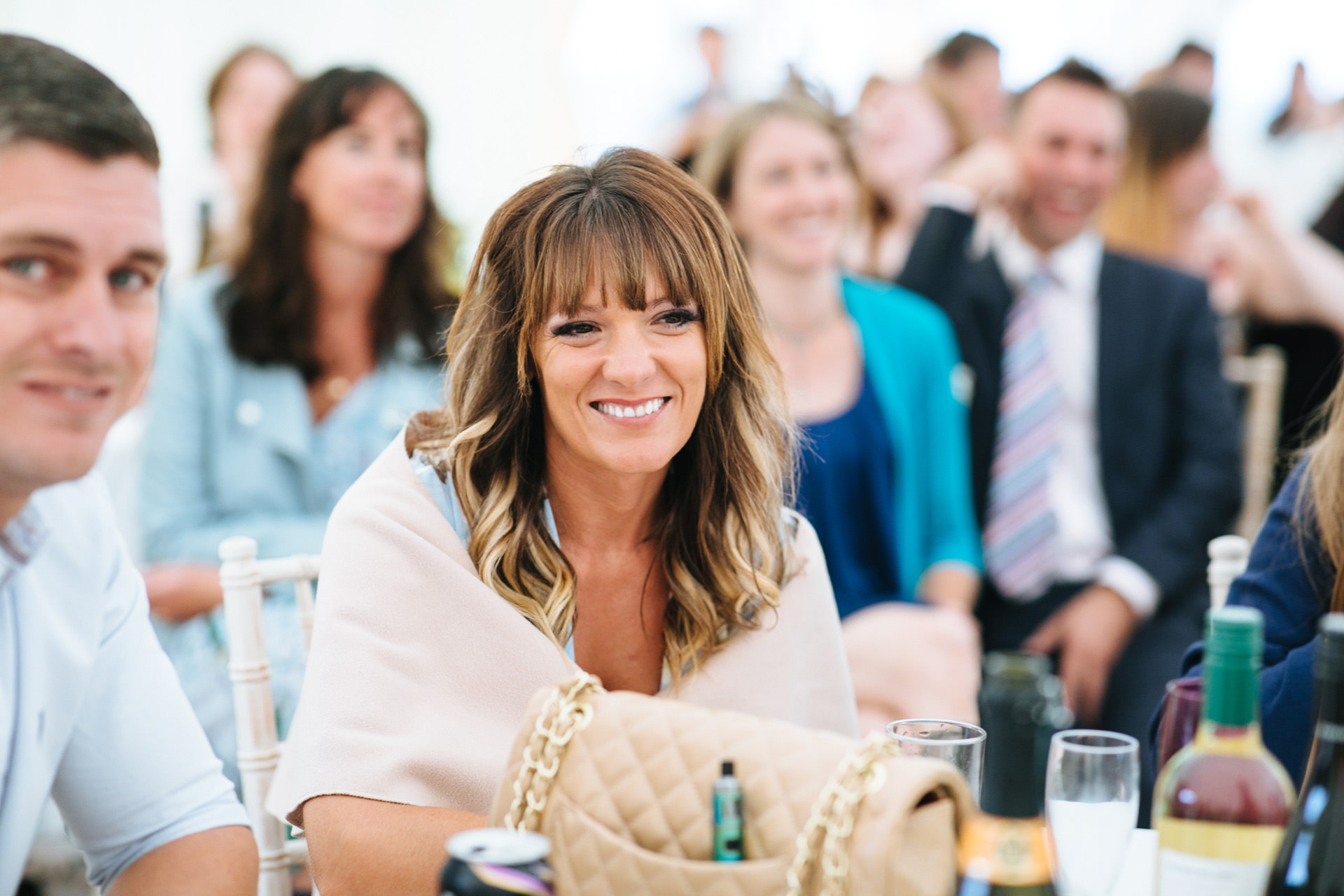 wedding guest smiling at speeches in rustic marquee