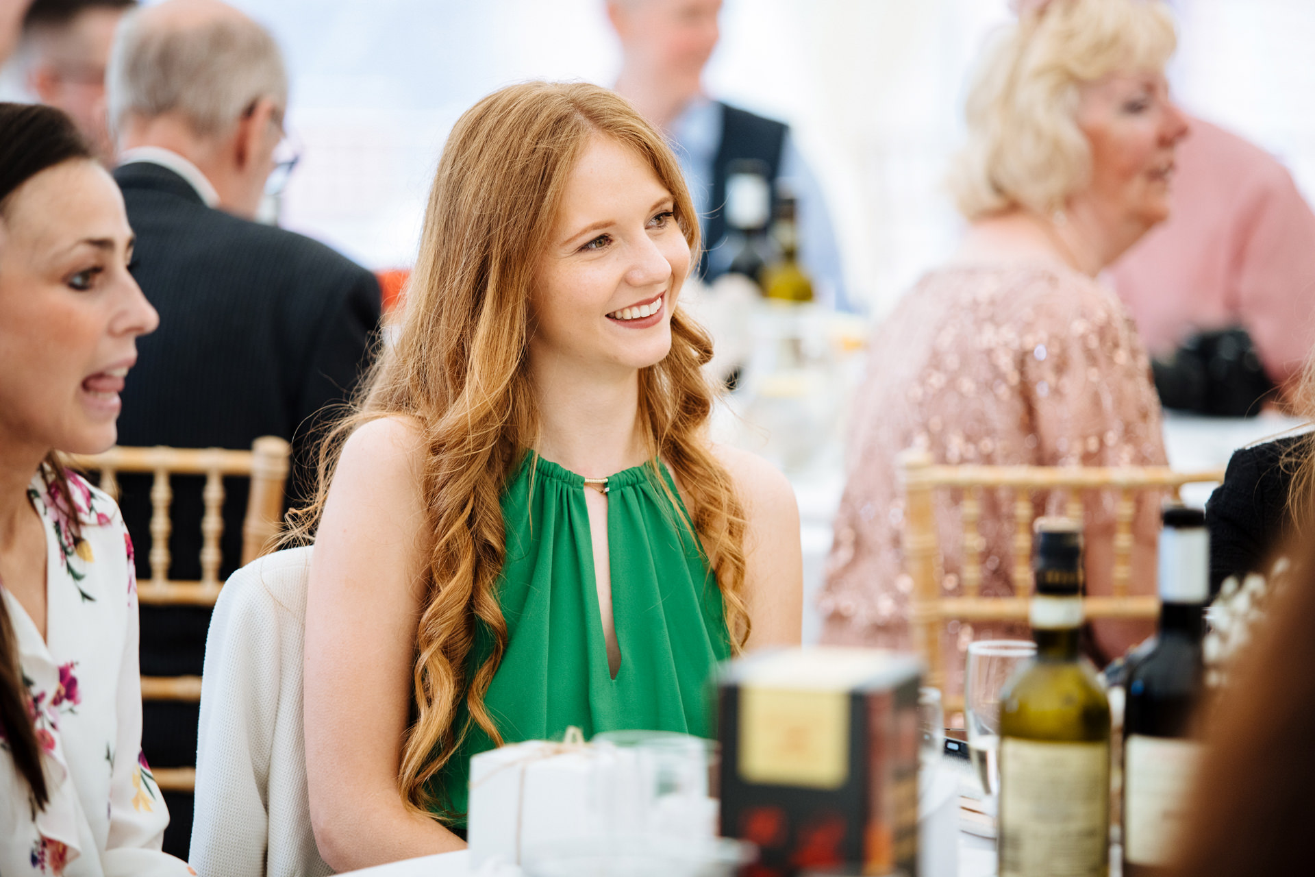 wedding guest with red hair and green dress laughing at speeches